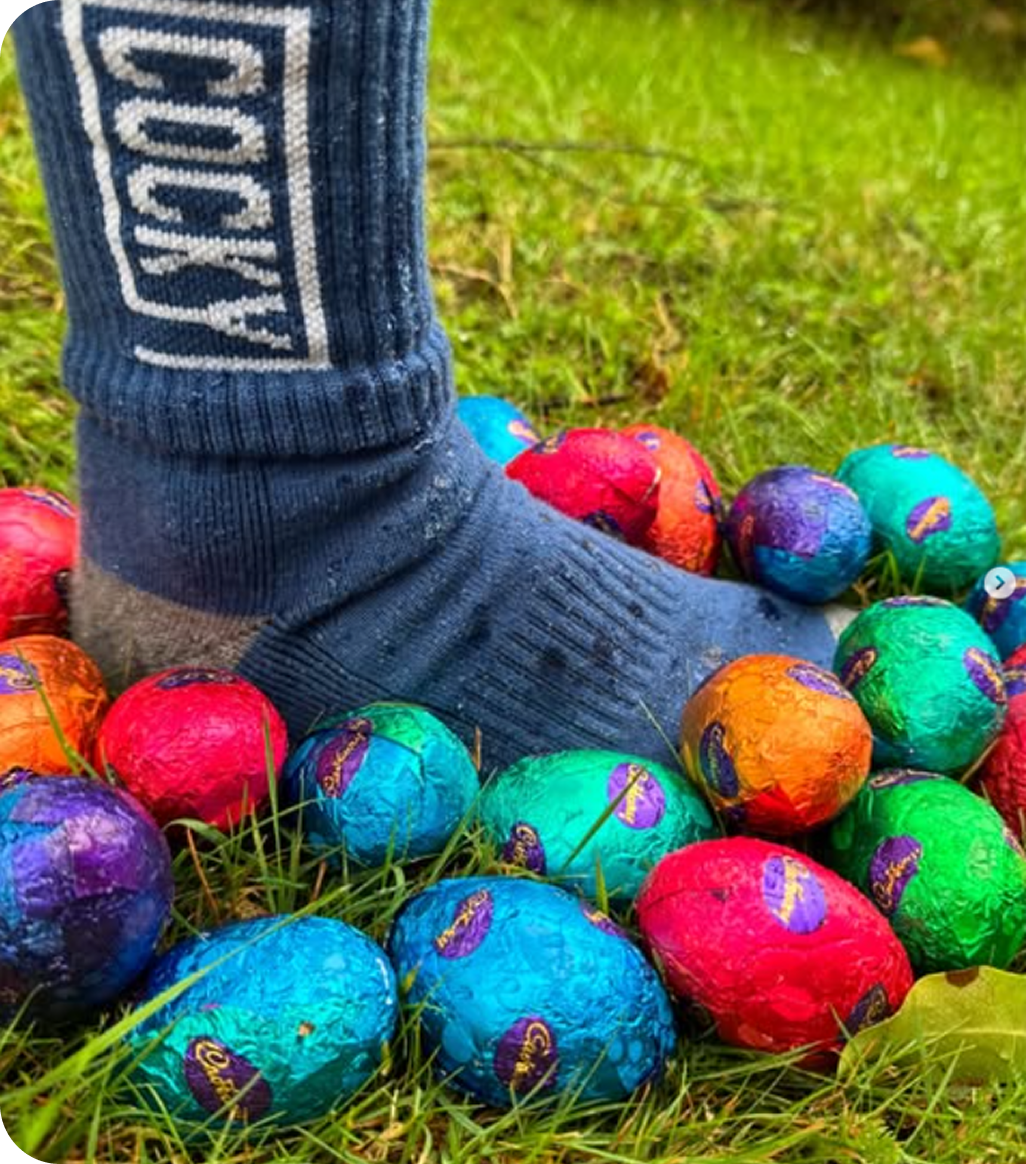 cocky socks on a kids foot stepping amongst easter eggs