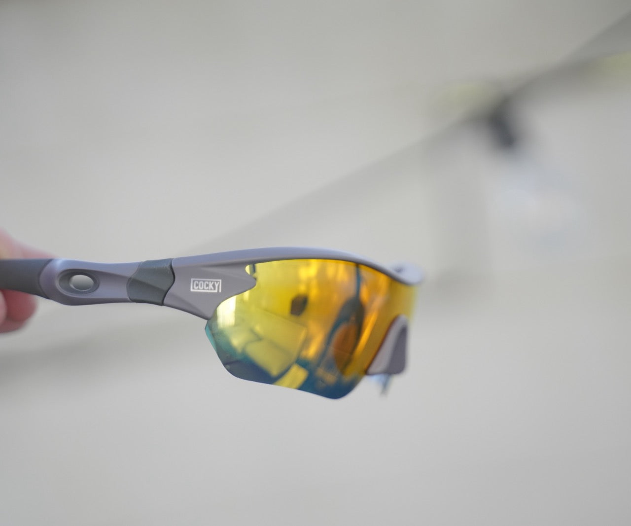 cocky sunglasses being held up sideways to show off the lens and logo
